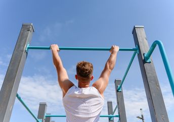 A man hangs from a bar.