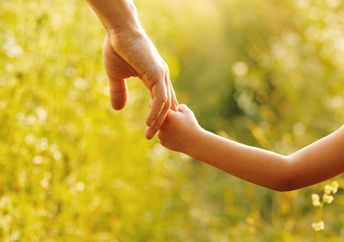 A parent holds the hand of a child.