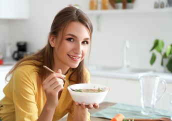 A woman eating hot chicken soup.