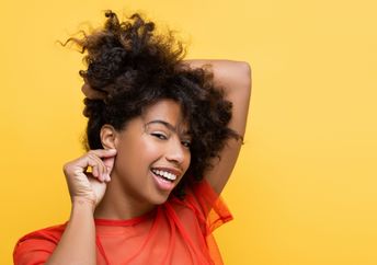 A woman touches her ear.