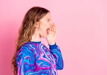 A young woman screams into an empty space.