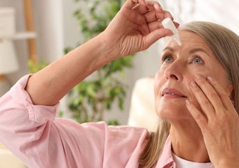 A senior woman using eye drops to improve her vision.