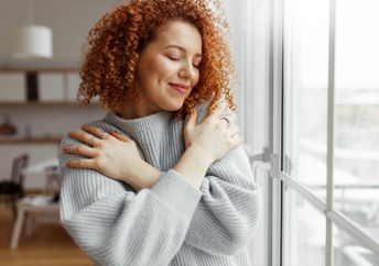 A woman hugs herself.