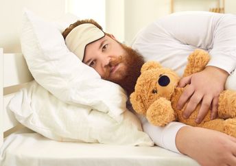 Adult man sleeping with a stuffed animal.