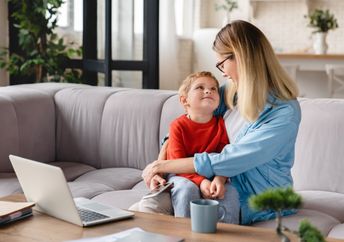 A mother and her child sit on a couch.
