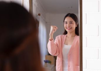 A woman smiles while looking at her reflection.