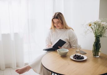 A woman sits and writes in a journal.