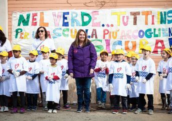Shari Arison stands with a group of children wearing “Doing Good” shirts.