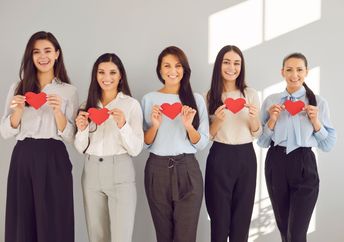 Women hold red paper hearts.