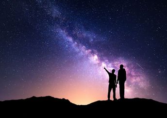 A silhouette of a family with a backdrop of the milky way.