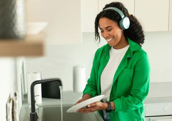 Woman listening to an audiobook while doing dishes.