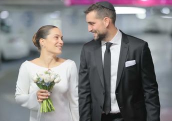 A couple holds hands on their wedding day in an underground shelter.