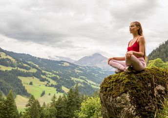 A woman meditates on a mountain.