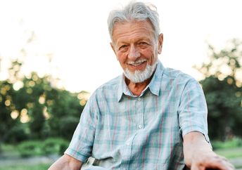 An elderly man smiling outdoors.