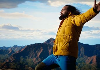 A happy adventurer standing at the top of a mountain.