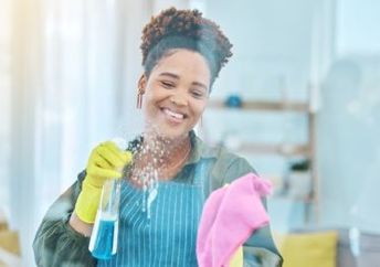 A smiling woman cleans a hospital window.