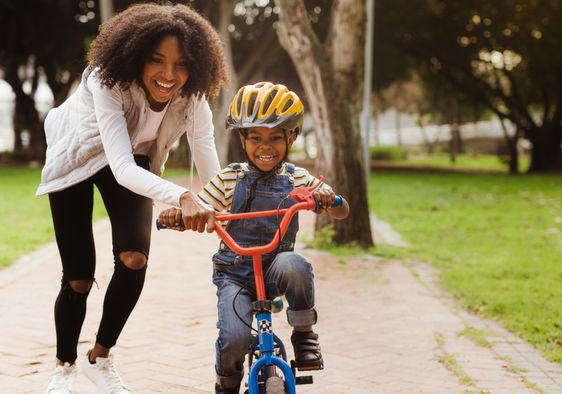 A mother teaching her child how to ride a bicycle.