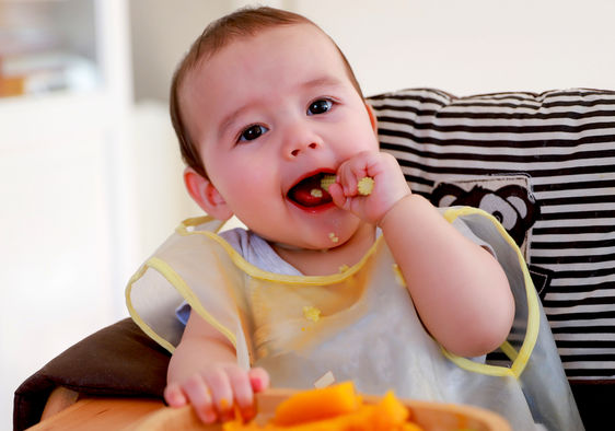 Cute baby eating cooked vegetables.