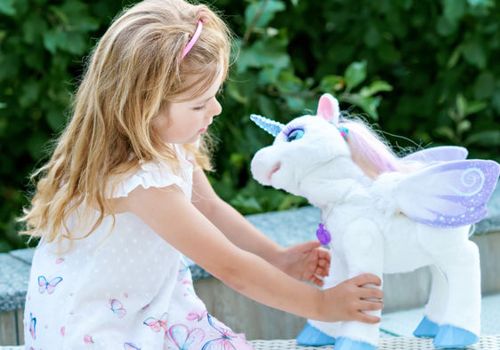 Girl playing with a unicorn plush toy.