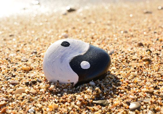 Yin and Yang painted on a rock by the sea.