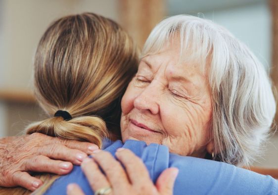 A woman hugs another woman.