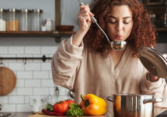 A woman boiling vegetables to make a healthy soup.