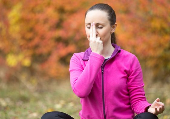 Woman practicing alternate nostril breathing.