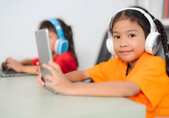 Two young students wear headphones.
