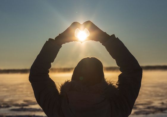 A woman makes a heart with her hands.