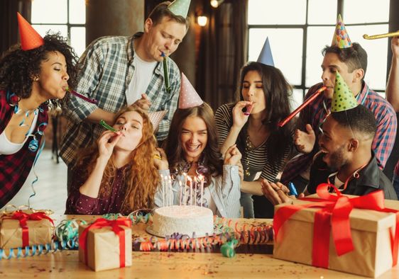 A group of friends celebrate together around a cake.