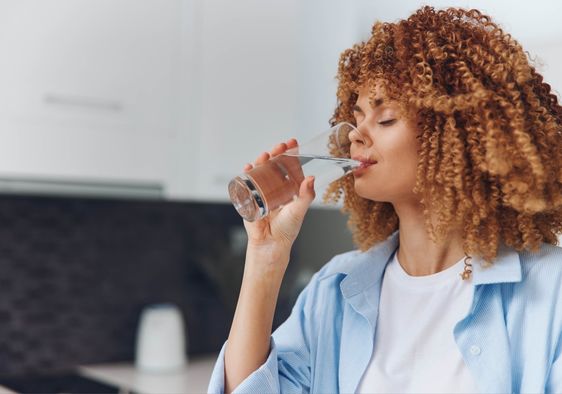 A woman drinks water from a glass.