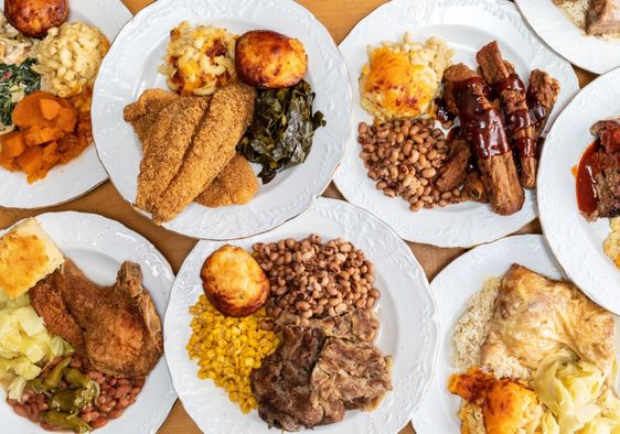 A soul food feast with a variety of dishes served on numerous plates.