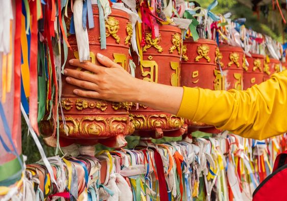 A pilgrim touches a turning spinning Buddhist prayer wheel.