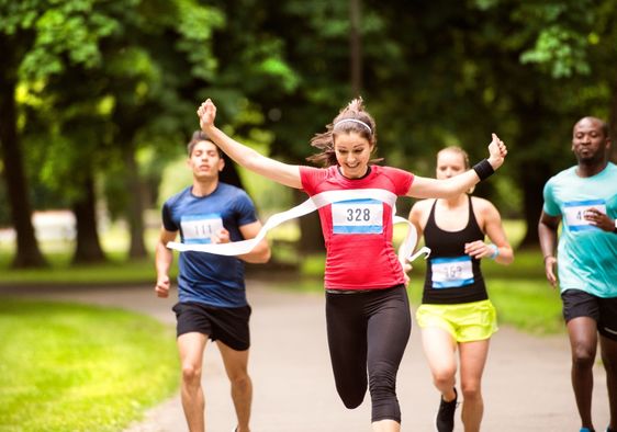 A woman runs in the crowd and crosses the finish line.