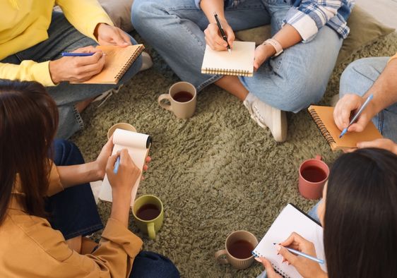 Young people write in notebooks.