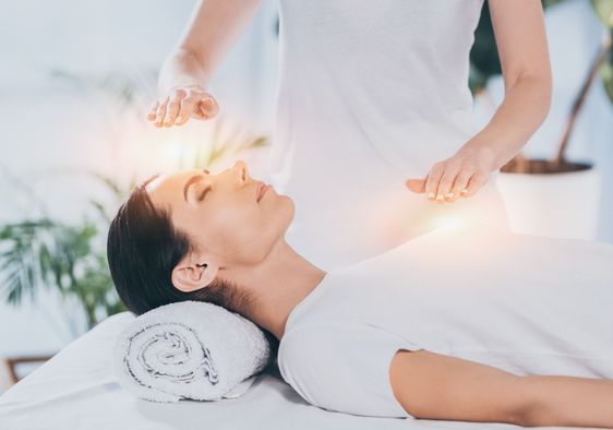 A calm woman receives reiki healing therapy.