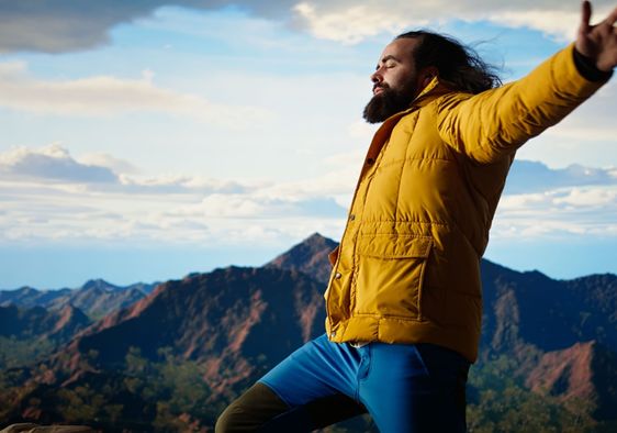 A happy adventurer standing at the top of a mountain.