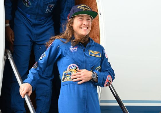 Christina Koch stands and smiles during the Artemis-02 crew return ceremony.