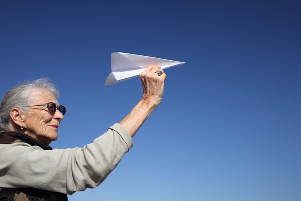 Happy older lady playing with paper plane