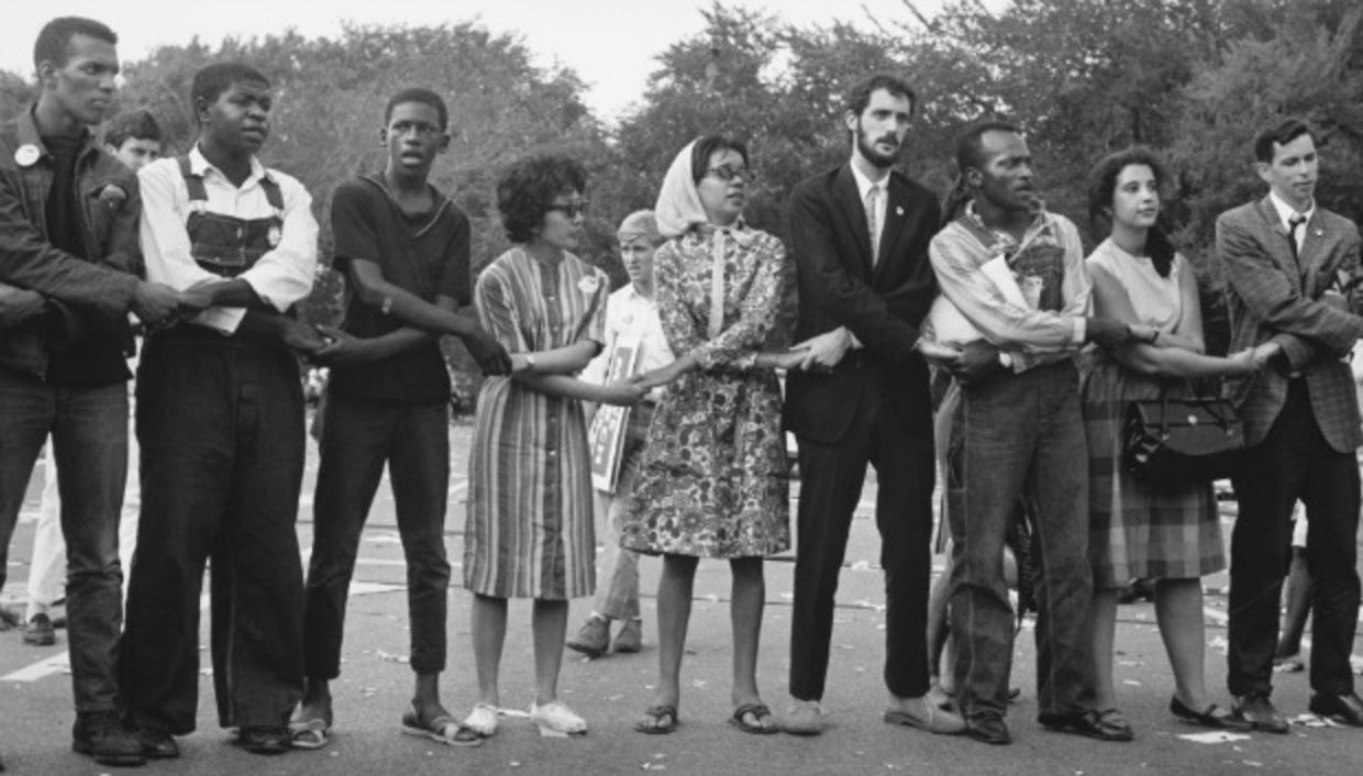 Blacks and white holding hands and singing during march on washington