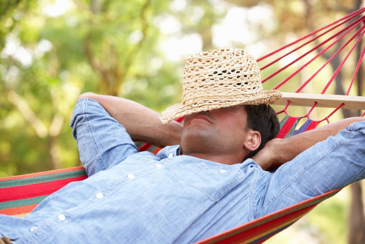 Man relaxing in hammock with hat covering his face