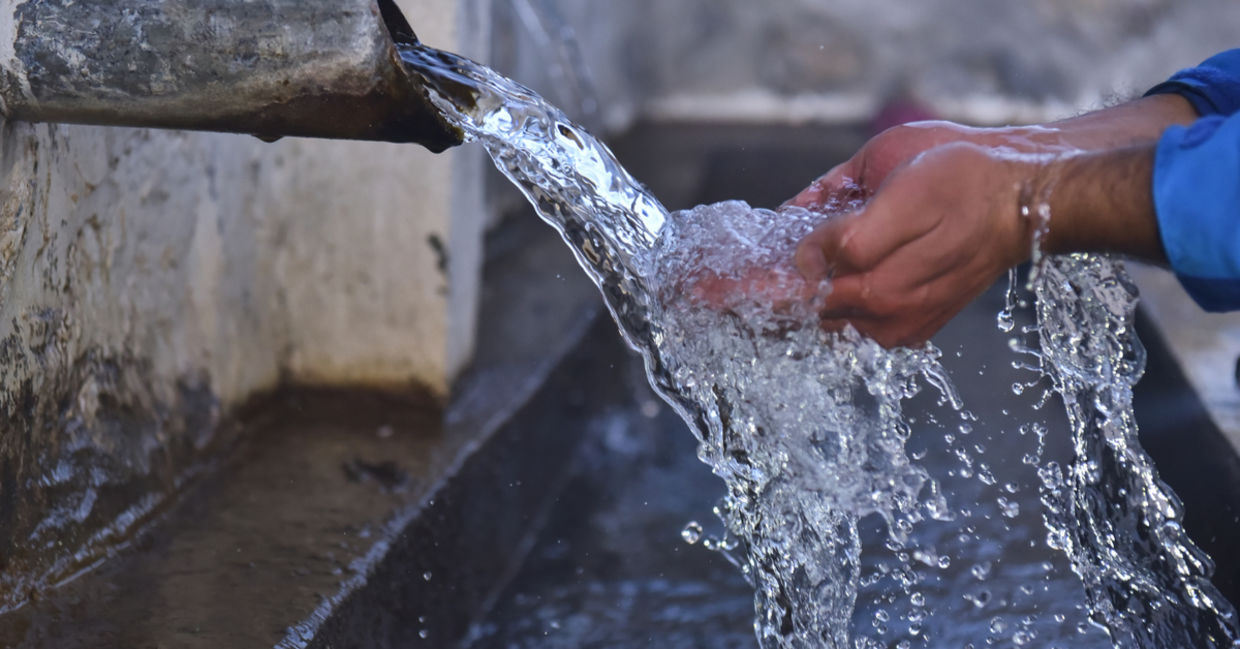 Clean water flows from a well into folded out hands