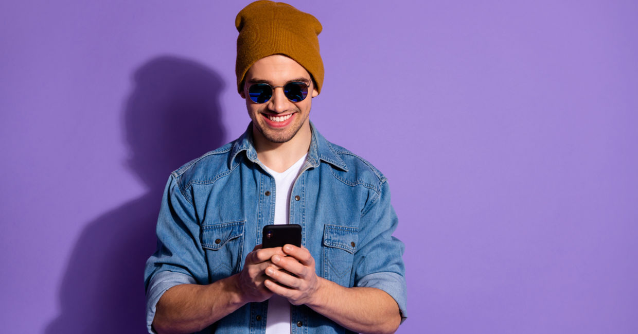 Smiling man on cellphone creates positivity using social media.