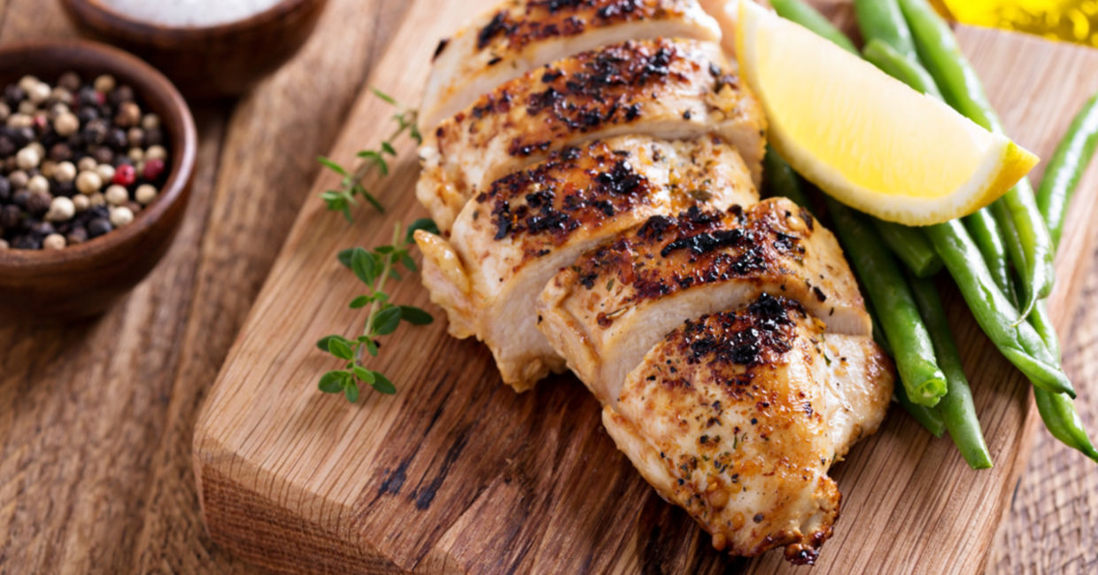 Sous vide chicken breast is served with a wedge of lemon and fresh thyme.