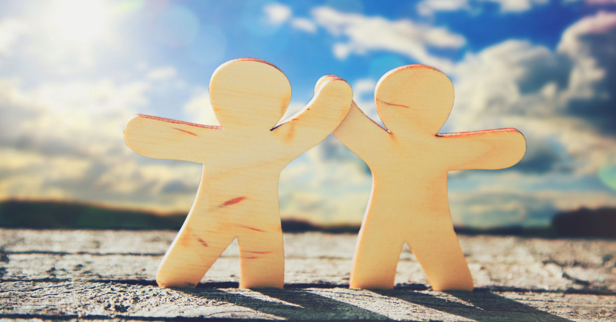 Wooden cutouts holding hands as a symbol of friendship.