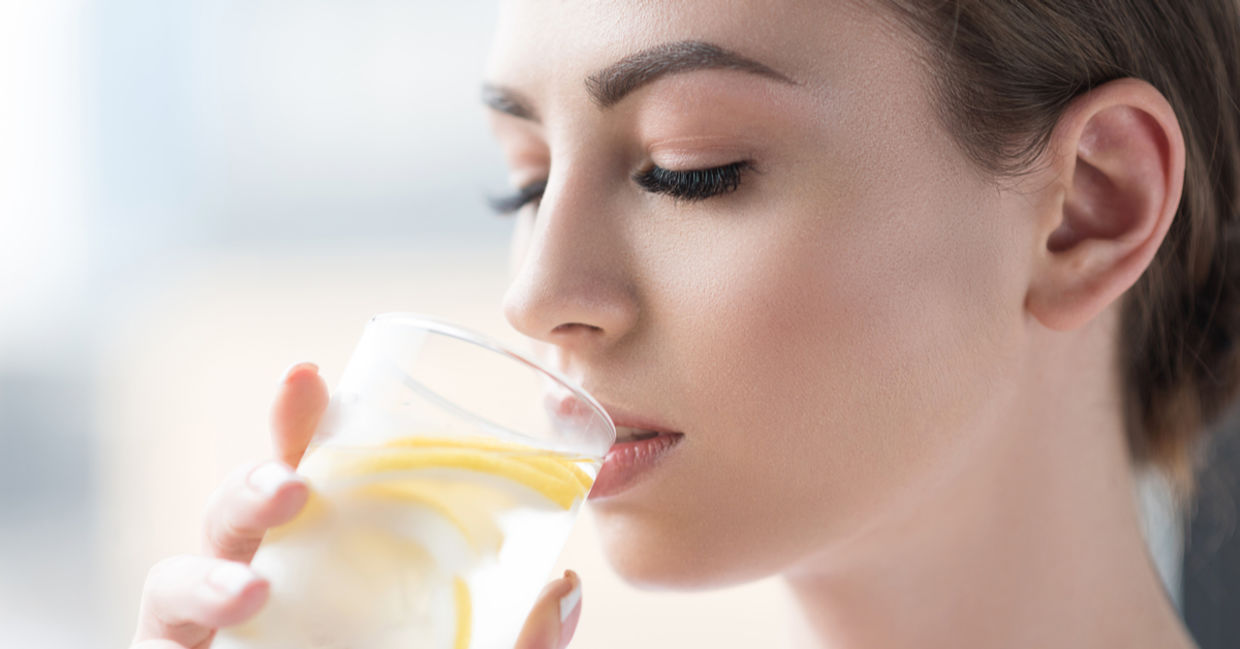 Woman drinking refreshing lemon water.
