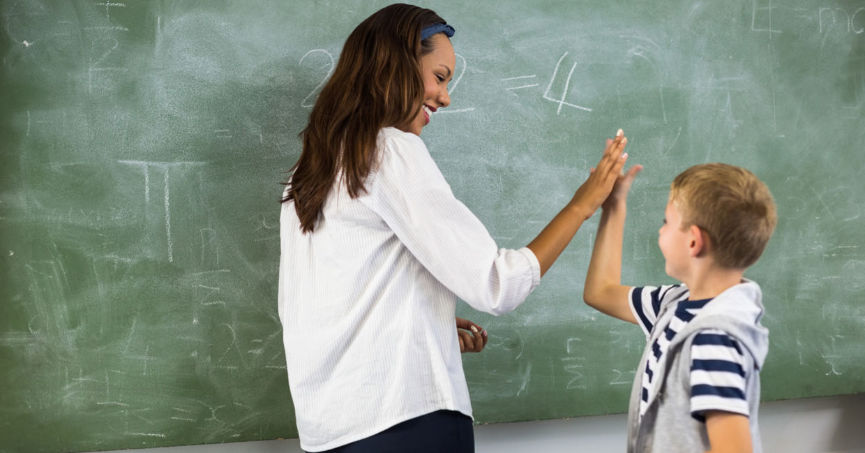 A teacher gives a student a high five.