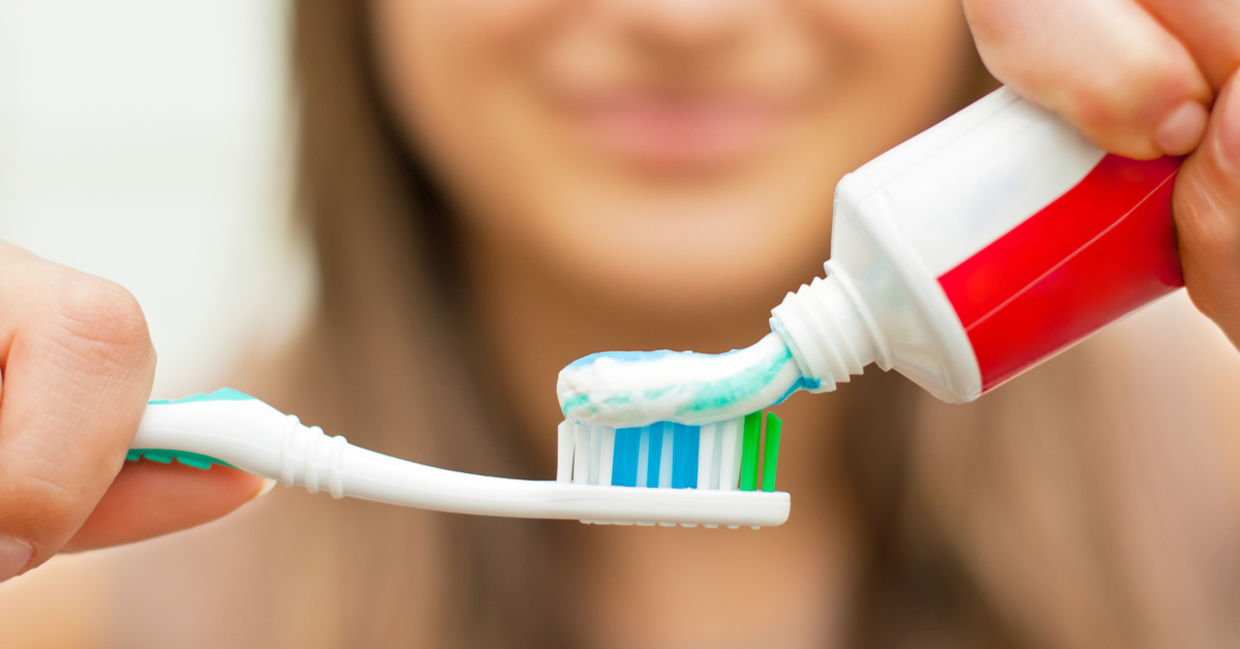 Woman putting toothpaste on a toothbrush.
