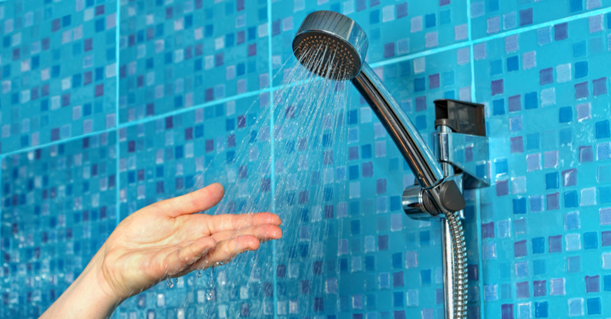 A woman checks the water flow on her reduced, low-flow shower faucet.
