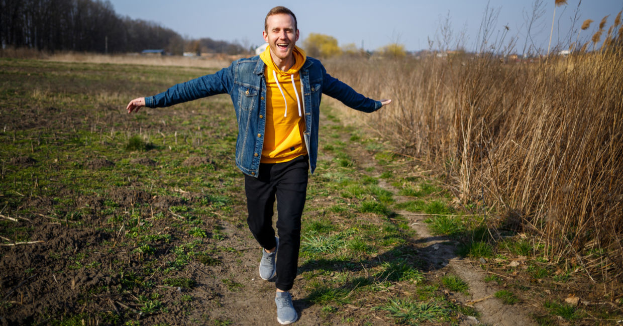 Smiling man feels elevated and free as he enjoys the simple life walking in nature.